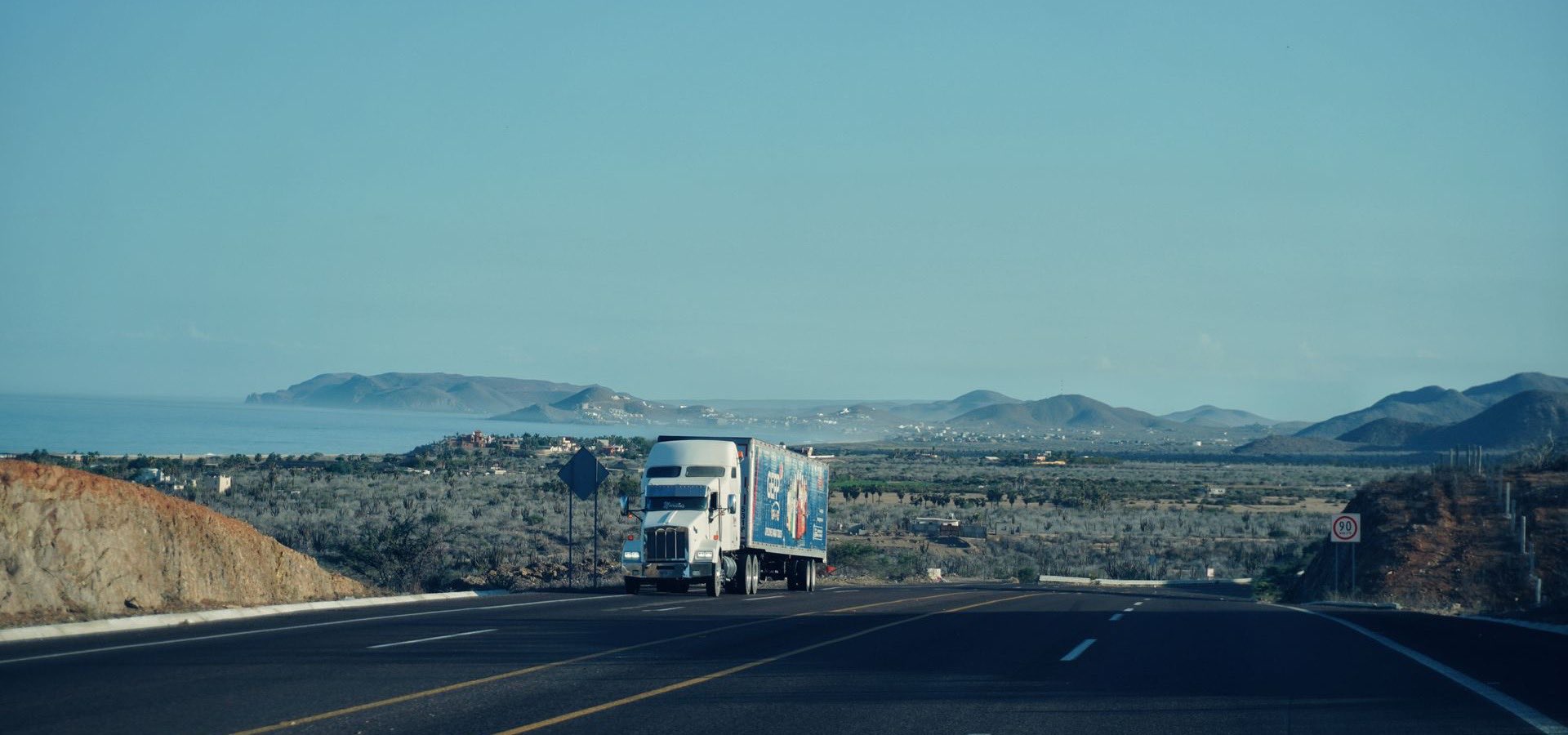 Articulated freight truck on a coastal road heading inland