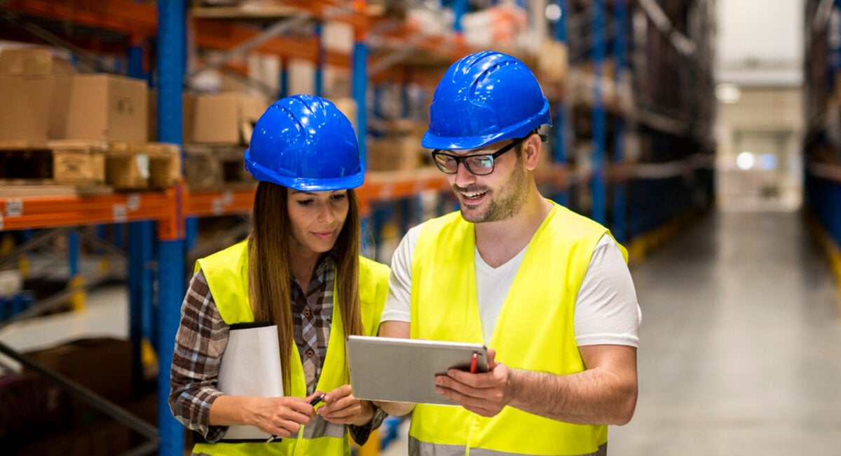 Warehouse supervisors reviewing stock on a tablet