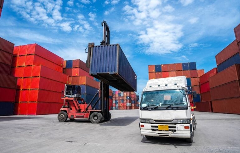 Container yard with reach stacker handling industrial cargo