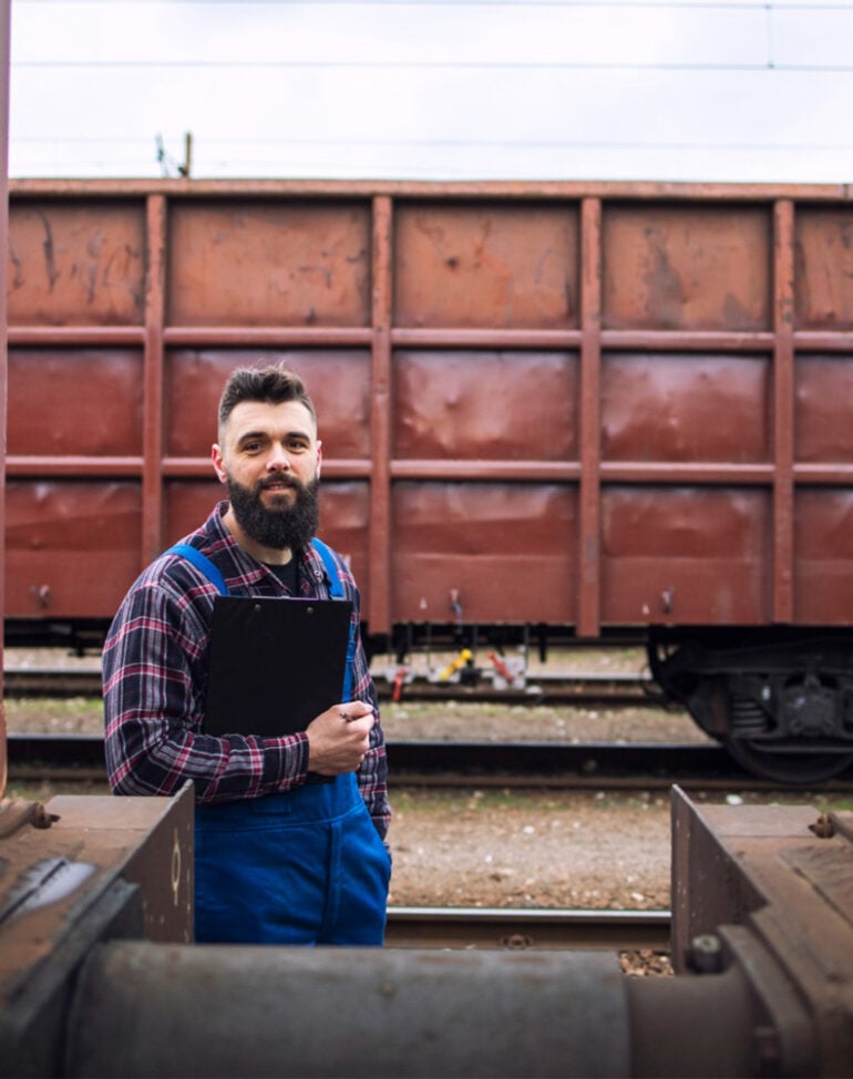 Inspector checking heavy industrial cargo loaded on rail wagons