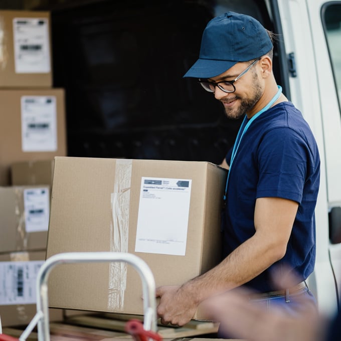 Courier loading a labelled parcel into a delivery van